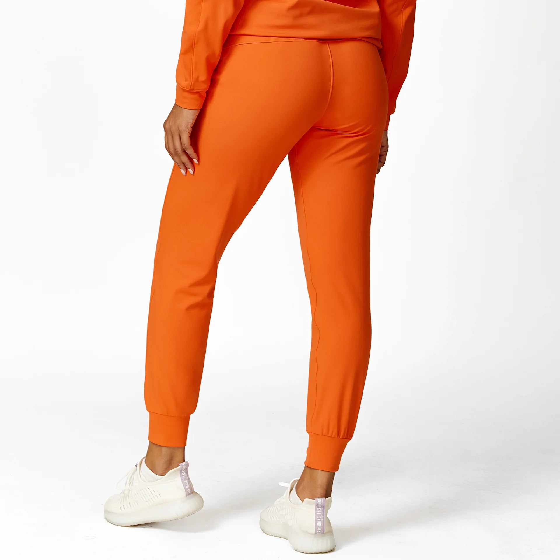 a woman wearing an orange sweat suit and white sneakers